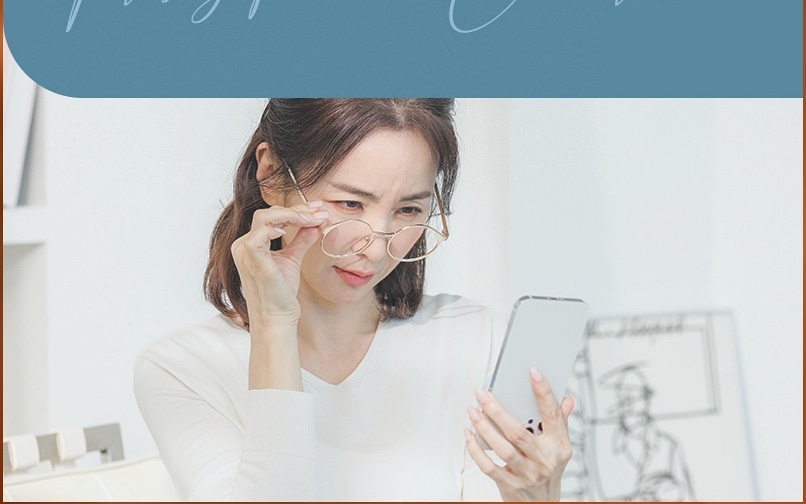 안경을 내리고 휴대폰 화면을 보는 여성
